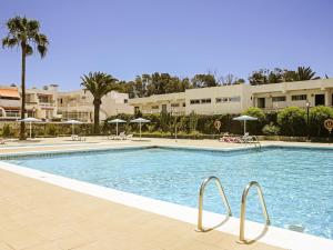 una piscina con sillas y sombrillas en un resort en Sunny Terrace Apartment Chaparral, en Las Galletas