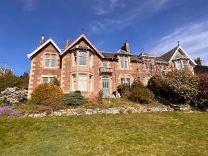 a large brick house with a lawn in front of it at Dungora House in Crieff
