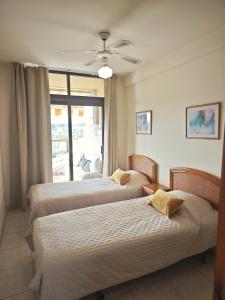 two beds in a room with a window at Big Ocean Terrace - Walk to Las Vistas Beach & Golden Mile in Los Cristianos