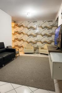 ein Wohnzimmer mit einem Sofa und einer Wand mit einem Wandbild in der Unterkunft Casa com 3 quartos e 1 suite - para 9 Pessoas in São Paulo