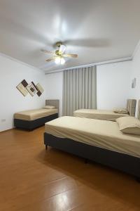 ein Schlafzimmer mit zwei Betten und einem Deckenventilator in der Unterkunft Casa com 3 quartos e 1 suite - para 9 Pessoas in São Paulo