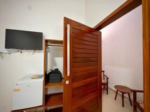 a room with a television and a wooden door at POUSADA TOCA DO LOBO in Ilha de Boipeba