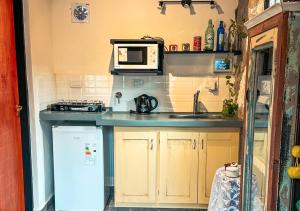 una cocina con fregadero y microondas en La Claudina - Cabañas Boutique en las Sierras, en Capilla del Monte