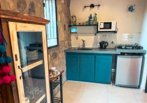 una pequeña cocina con armarios azules y microondas en La Claudina - Cabañas Boutique en las Sierras, en Capilla del Monte