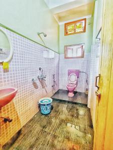 a bathroom with a pink toilet and a sink at Jonaki Abax Homestay in Nowgong