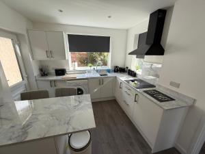 Una cocina con gabinetes blancos y encimera. en Beach Side Bungalow, en Saint Annes on the Sea 16 fotos más