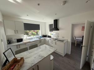 cocina con armarios blancos y encimera de mármol en Beach Side Bungalow, en Saint Annes on the Sea