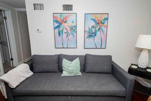a couch in a living room with three paintings on the wall at Slow Pace Beach Living - Pool - Steps from Beach in Jacksonville Beach