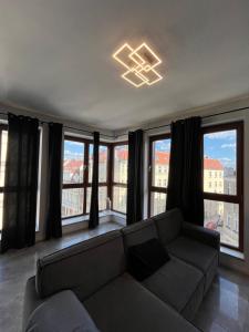 a living room with a couch in front of windows at Windows to the City Stylish Apartment in Poznań