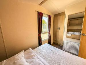 a small bedroom with a bed and a window at Cosy Caravan With Decking At Oaklands Holiday Park In Essex Ref 39042Cf in Clacton-on-Sea +13 photos