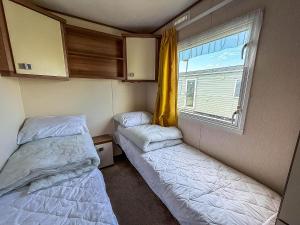 two beds in a small room with a window at Superb Caravan At Steeple Bay Holiday Park In Essex, Sleeps 6 Ref 36081D in Southminster +16 photos