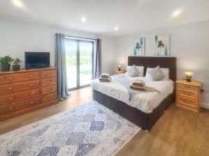 a bedroom with a large bed with a television and a dresser at The Bungalow - Uk38049 in West Pennard