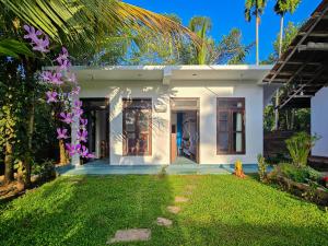 a white house with purple flowers in the yard at Sammy Villa Tangalle in Tangalle