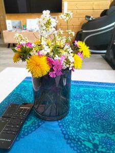 a vase filled with flowers sitting next to a remote control at City Light in Tornio