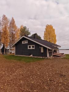 a black house sitting on top of a field at Willa Mäntyniemi in Impiö