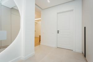 a hallway with white walls and a door at Apartment lux in Chişinău +1 photo