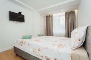 a white bedroom with a bed and a flat screen tv at Apartment lux in Chişinău