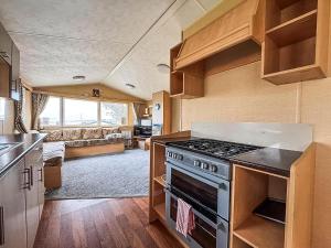 a kitchen with a stove and a living room at Homely, Dog Friendly Caravan At Sand Le Mere In Yorkshire Ref 71005O in Tunstall