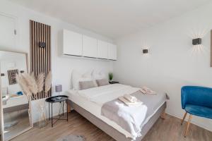 a white bedroom with a bed and a blue chair at SpaceStays Bunker Messe Apartment Wi-Fi TV in Essen
