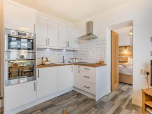 a kitchen with white cabinets and stainless steel appliances at Driftwood - Uk34192 in Goodrington