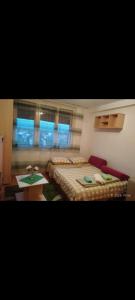 ein Schlafzimmer mit einem Bett und einem Tisch und Fenstern in der Unterkunft Apartman Milic in Jagodina