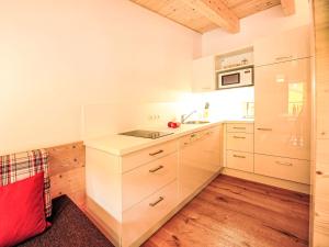 a kitchen with white cabinets and a red pillow at Studio Alpelux-2 by Interhome in Jerzens