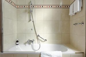 a bathroom with a bath tub with a shower at hideauts hotels Villa R in Vienna +46 photos