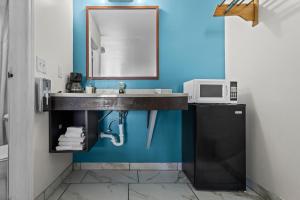 a bathroom with a sink and a microwave at Capital O First Heritage Inn Rantoul IL I 57 in Rantoul