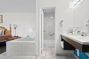 a bathroom with a tub and a shower and a sink at Capital O First Heritage Inn Rantoul IL I 57 in Rantoul +52 photos