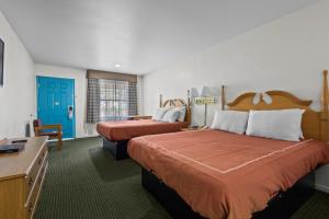 a hotel room with two beds and a blue door at Capital O First Heritage Inn Rantoul IL I 57 in Rantoul
