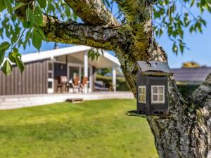 Holiday Home Quanna - 450m from the sea by Interhome في Hejlsminde: بيت الطيور على شجرة أمام منزل