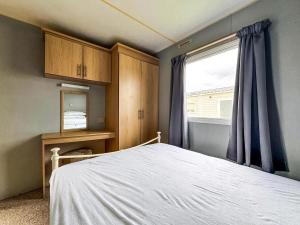 a bedroom with a bed and a window at Lovely 8 Berth Caravan At Harts Holiday Park In Kent Ref 74066B in Sheerness