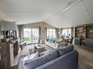 ein Wohnzimmer mit Sofa und Tisch in der Unterkunft Stunning Lodge At Seaview Holiday Park In Kent Ref 47012Pb in Whitstable