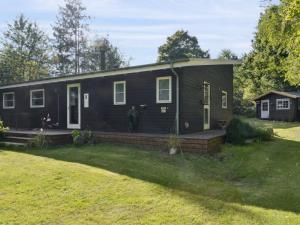 a black house with a porch and a yard at Holiday Home Erikke - 575m from the sea by Interhome in Nyrup