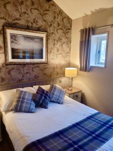 a bedroom with a bed with blue plaid pillows at Kings Arms Hotel in Holme +25 photos