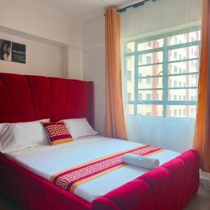 a bed with a red headboard next to a window at 1&2&3bedroom KlenCBDMilimani apartments in Kisumu