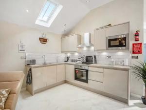 eine Küche mit weißen Schränken und einem Herd mit Backofen in der Unterkunft Peewit Cottage-Ukc6986 in Castleside