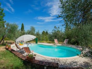 a swimming pool with chairs and an umbrella at Holiday Home Villa Albertine by Interhome in Fattoria Spedaletto