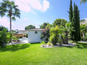 a garden with palm trees and a white building at Villa Serenidad by Interhome in Casas de Torrat