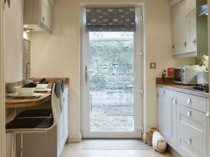 a kitchen with a door leading to a window at Easter Cottage in Bamford