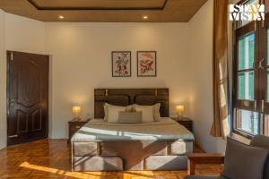 a bedroom with a bed with two lamps and a window at StayVista at Lakeside Panorama with Lawn & Wi-Fi in Srinagar
