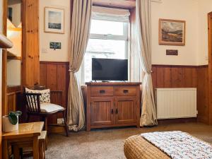 a bedroom with a tv and a bed and a window at Kirkton in Castle Douglas