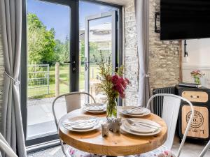 a wooden table with chairs and a vase of flowers on it at The Old Cowsheds 2 - Shippon - Uk49787 in Cribyn