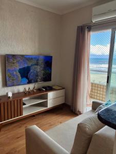 een woonkamer met een flatscreen-tv en een bank bij Apto lado Praia - Vista MAR in Praia Grande