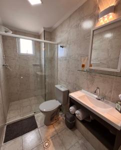 een badkamer met een douche, een toilet en een wastafel bij Apto lado Praia - Vista MAR in Praia Grande