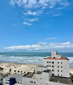 een uitzicht op een strand met een gebouw en de oceaan bij Apto lado Praia - Vista MAR in Praia Grande