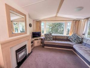 a living room with a couch and a fireplace at Cosy Caravan With Decking At Oaklands Holiday Park In Essex Ref 39042Cf in Clacton-on-Sea
