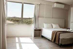 São Gonçalo do Rio AbaixoSG Apart Hotel的带一张床和两扇窗户的卧室