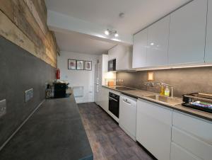 una grande cucina con mobili bianchi e un lavandino di Ashdale Cottage with Sauna, Plunge Pool, Games Room, Kit Drying Room a Isle of Arran