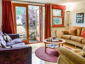 a living room with a couch and a table at Oakwood Cottage - Glencoe in Glencoe